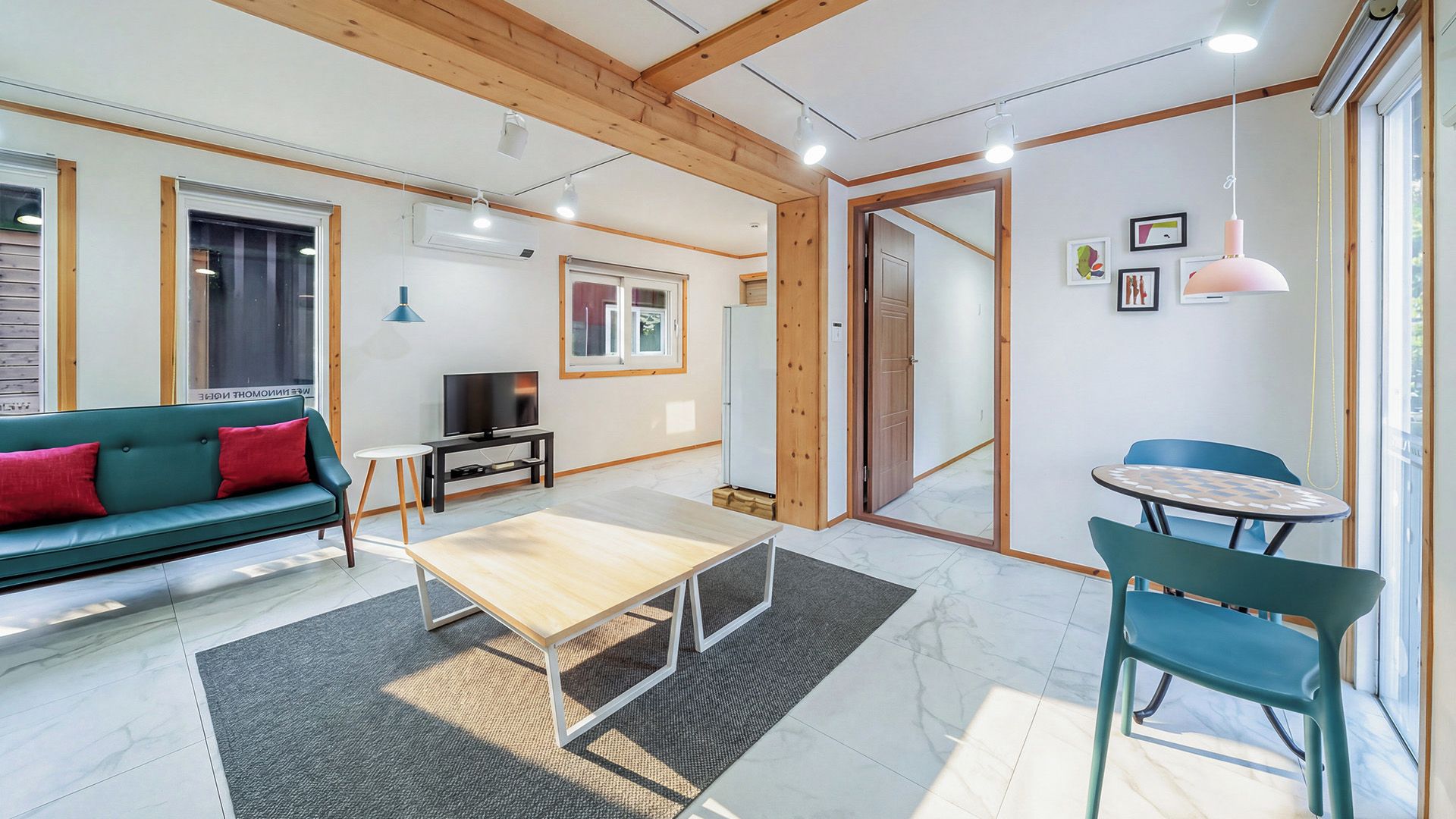 Una sala de estar moderna con un sofá, una mesa de centro, un televisor y un comedor con sillas.