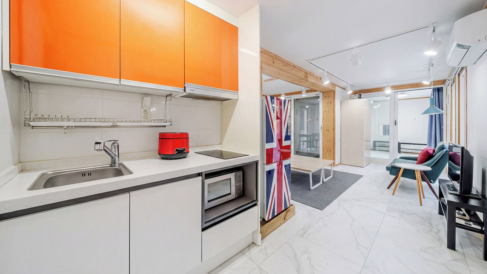 Una cocina moderna con armarios blancos, un electrodoméstico rojo y un comedor con mesa y sillas.