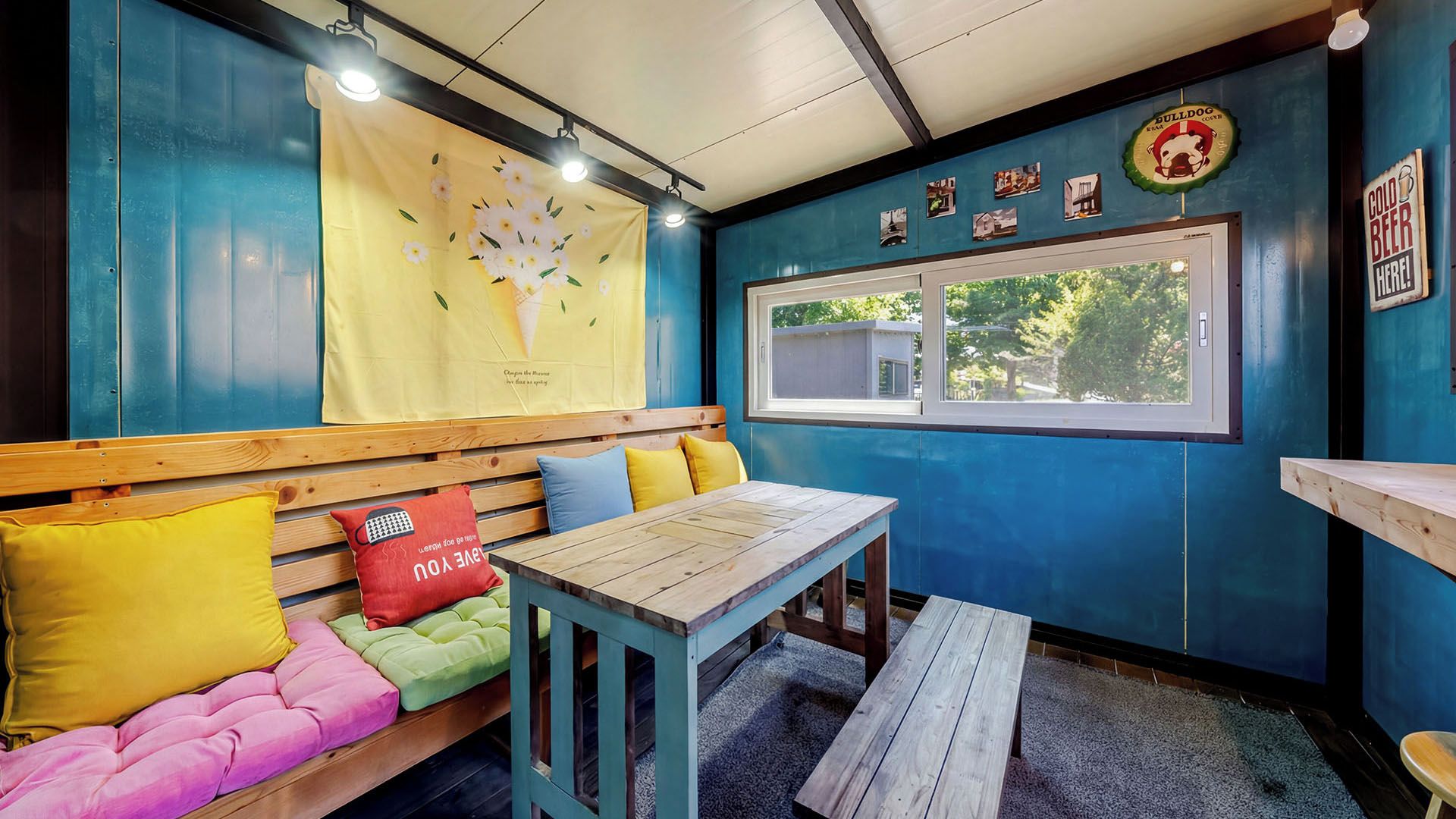 A cozy seating area with a bench and a table, a window with a view, and a wall with a sign.