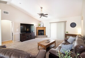 A living room with a television, fireplace, ceiling fan, and a brown leather couch. - Close to River & Avi Casino - Boat Parking, BBQ & Dogs OK! (Fort Mohave)