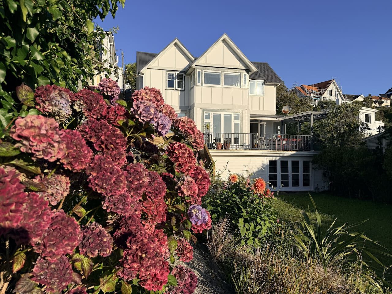 A two-story house with a balcony, surrounded by a well-maintained garden with hydrangeas.