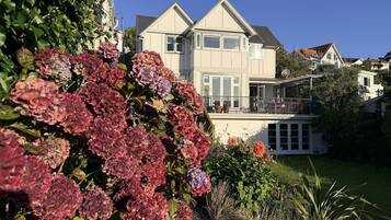 A two-story house with a balcony, surrounded by a well-maintained garden with hydrangeas.