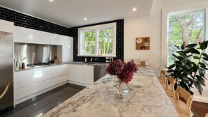 Una cucina moderna con mobili bianchi, un piano di lavoro in marmo e una schiena di rivestimento nera.