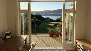 Un balcone con vista su una città e sull'acqua, con un tavolo di legno, sedie e piante in vaso.