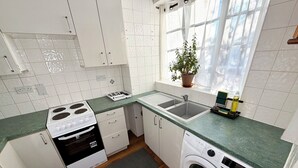 Una cocina moderna con armarios blancos, horno empotrado, lavaplatos y lavadora.