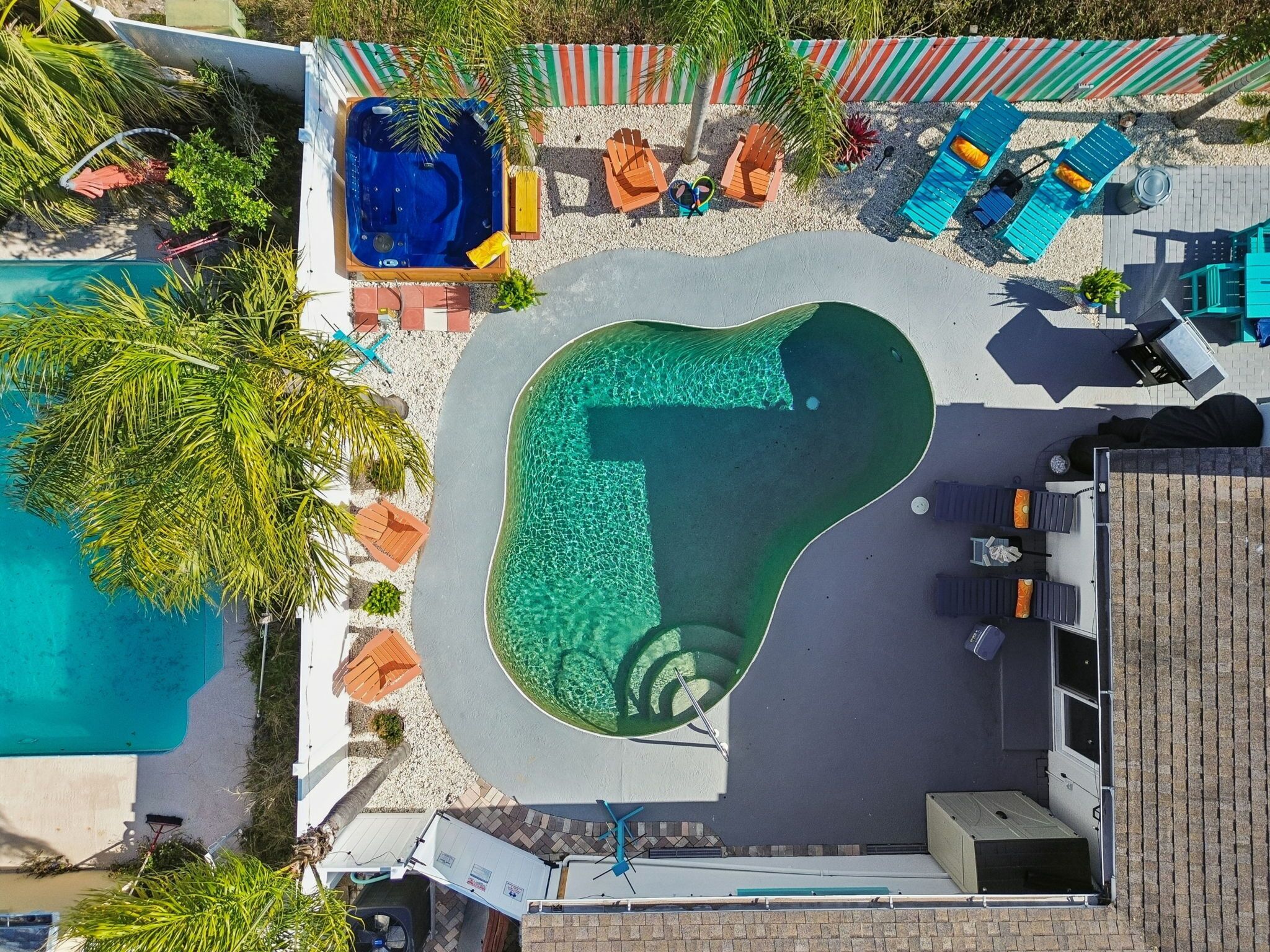 Eine Vogelperspektive eines Poolbereichs mit Whirlpool, Liegestühlen und einer kleinen Terrasse.
