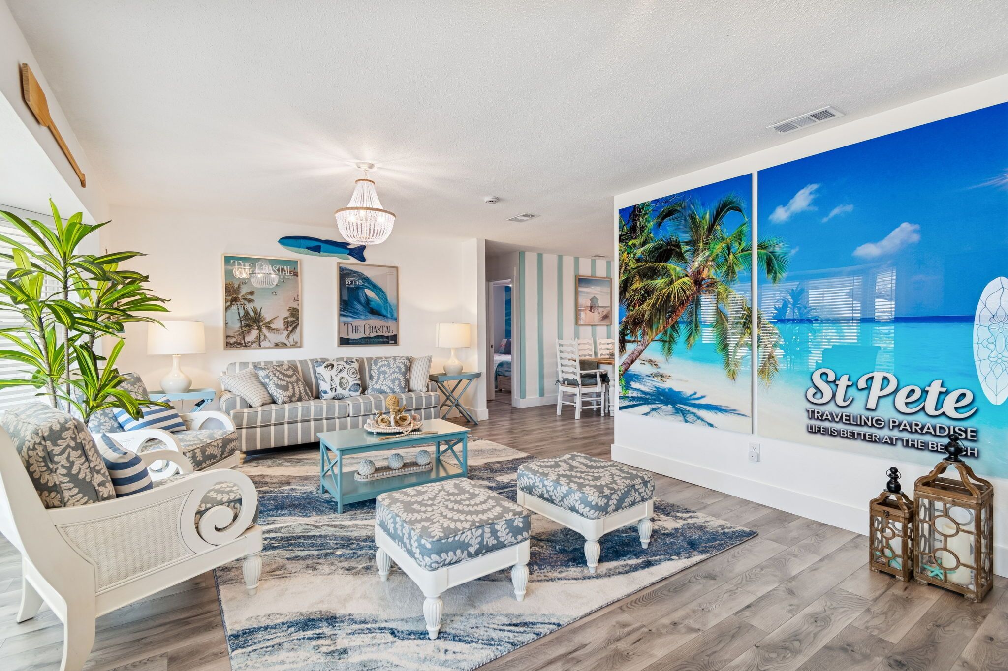 Amplia sala de estar con un mural grande con temática de playa, un conjunto de sofás cómodo y un comedor.