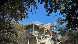 Un immeuble à plusieurs étages doté d’une terrasse et d’un escalier en bois, entouré d’arbres.