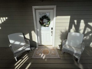 A front porch with a white door, two wicker chairs, and a doormat. - Panoramic Hill Country Rooftop View Wedding & Event Venue (Leander)