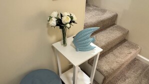 Une petite table blanche ornée d’un vase de fleurs blanches et d’un objet décoratif bleu.
