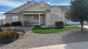 A single-story house with a front porch, a garage, and a well-maintained lawn. - Newly Remodeled Mountain Escape Near Casino + Pool Table + Putting Green (Rio Rancho)