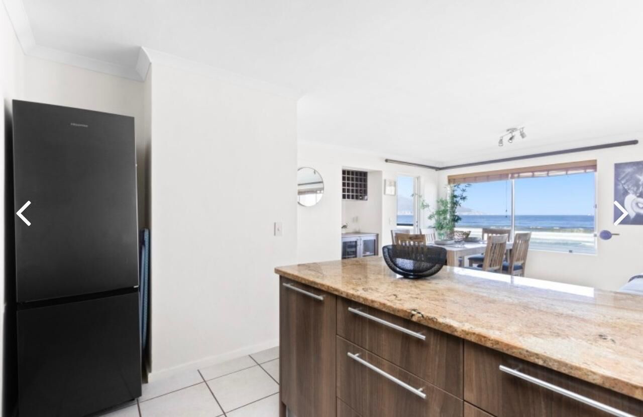 A modern kitchen with a black refrigerator, wooden cabinets, and a granite countertop.