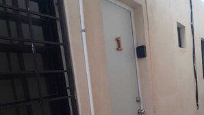 A beige building with a door marked '1', a barred window, and a small window on the right.