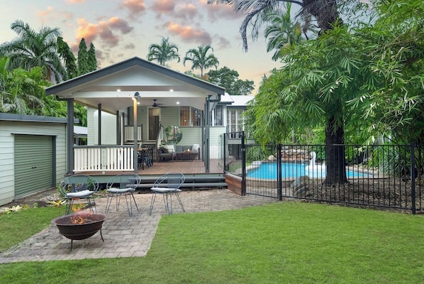 A house with a covered patio, a swimming pool, and a fire pit.