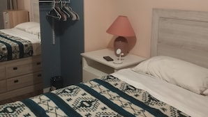 Ein Schlafzimmer mit zwei Betten, einem Schrank, einem Nachttisch mit Lampe und einem gerahmten Bild an der Wand.