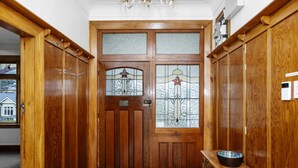 Eine hölzerne Doppeltür mit Glasscheiben und einem Blumendesign, umrahmt von Holzschränken und einer Bank mit einer Schale.