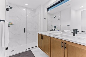 Une salle de bain moderne avec une douche à parois de verre, un grand miroir et des meubles en bois.