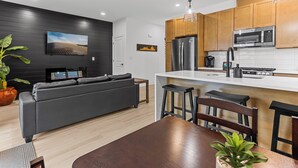 Una cocina moderna con un refrigerador negro, armarios de madera y una encimera blanca.