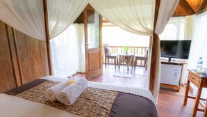 A room with a bed, a TV, and a balcony. - Room-deluxe Bungalow at Doni House (Ubud)