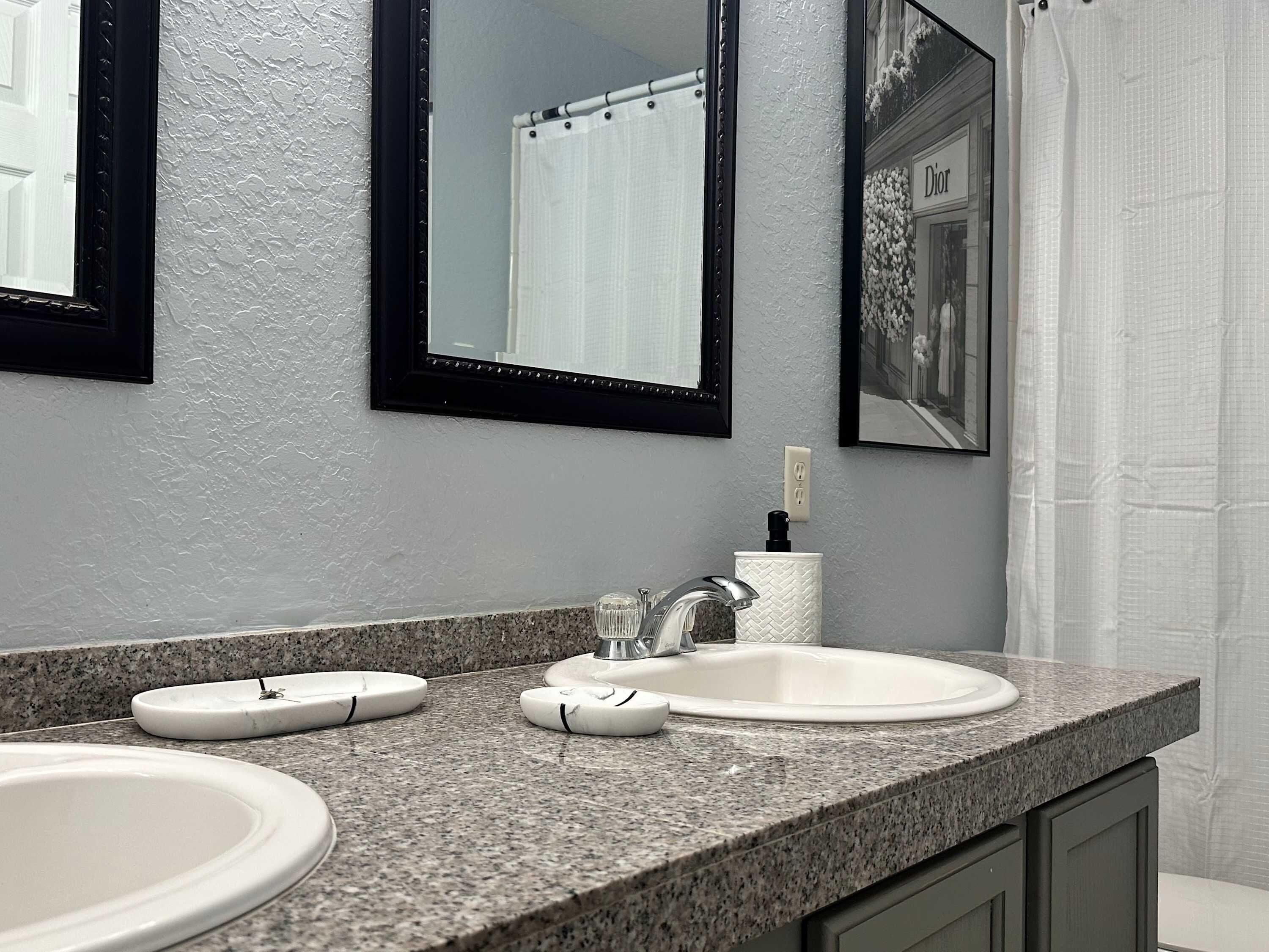 A bathroom with two sinks, a mirror, and a shower curtain.