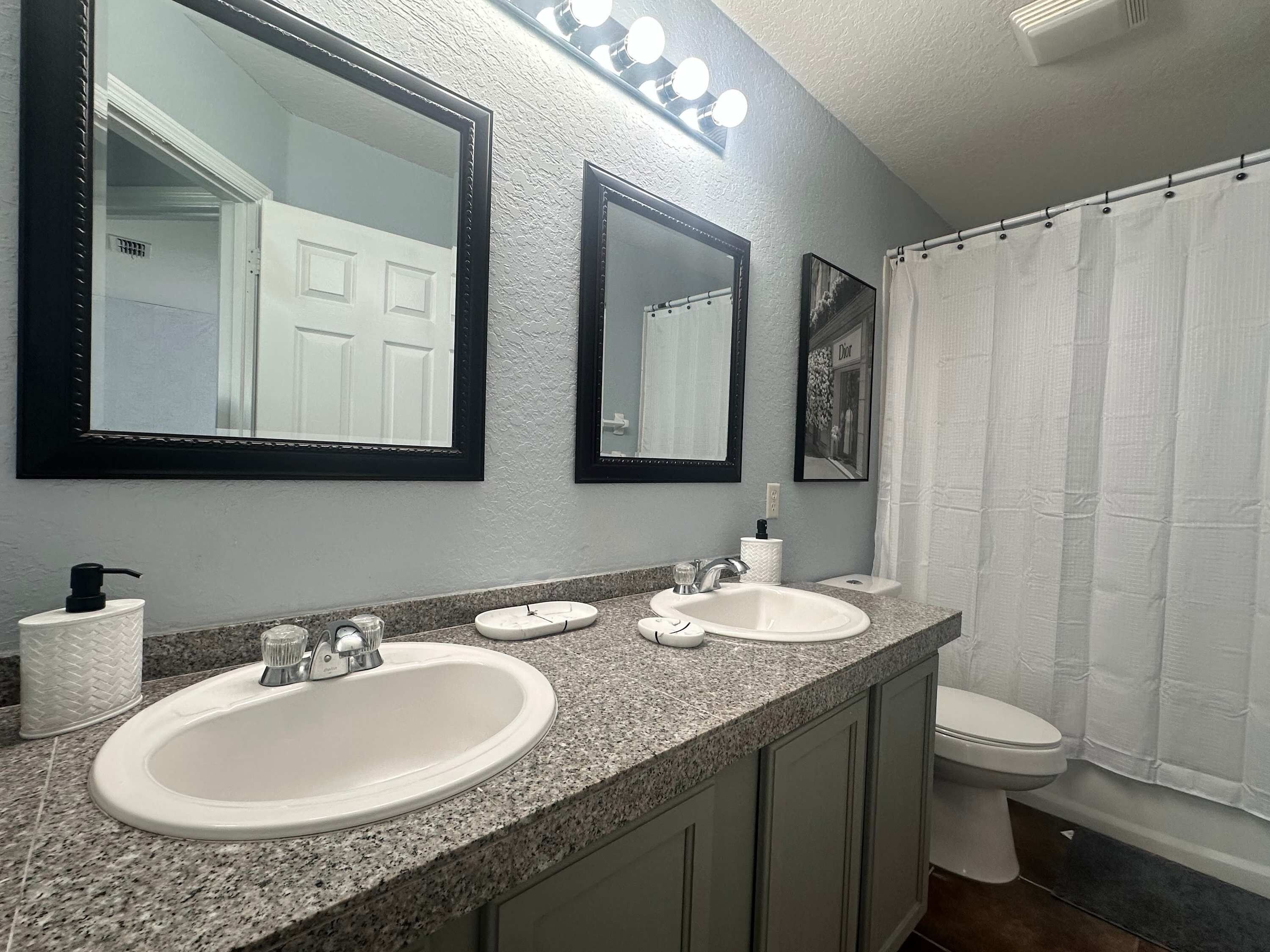 A bathroom with two sinks, a toilet, and a shower curtain.
