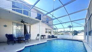 An indoor swimming pool with a glass ceiling, a ceiling fan, and blue chairs around a table. - Family Villa 5 bedroom near disney world 5 Villa (Davenport)