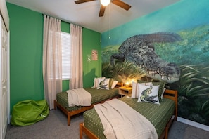 A room with two beds, a ceiling fan, a green wall, a mural of a crocodile, and a window with curtains. - Wildlife Themed Villa 4 Bd Pool Near Disney 4 Bedroom Home (Davenport)