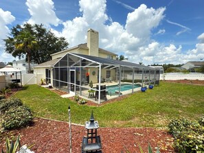 A house with a covered outdoor area, a swimming pool, and a well-maintained lawn. - Near Disney Villa 3 Bd Private Pool 3 Bedroom Home (Davenport)