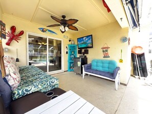 A covered outdoor seating area with a ceiling fan, a blue sofa, a white table, and a teal storage unit. - Near Disney Villa 3 Bd Private Pool 3 Bedroom Home (Davenport)