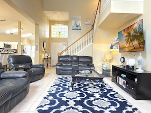 A spacious living room with a large sofa set, a coffee table, and a staircase leading to an upper level. - Near Disney Villa 3 Bd Private Pool 3 Bedroom Home (Davenport)