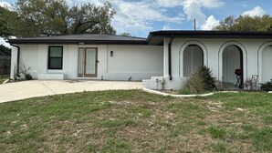Ein eingeschossiges Haus mit Eingangstür, kleiner Veranda und gepflegtem Rasen.