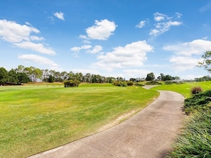 A golf course with a concrete pathway curving through the grass. - 3bd Villa With Private Pool & Golf Walmart 2 Min 3 Bedroom Home (Haines City)