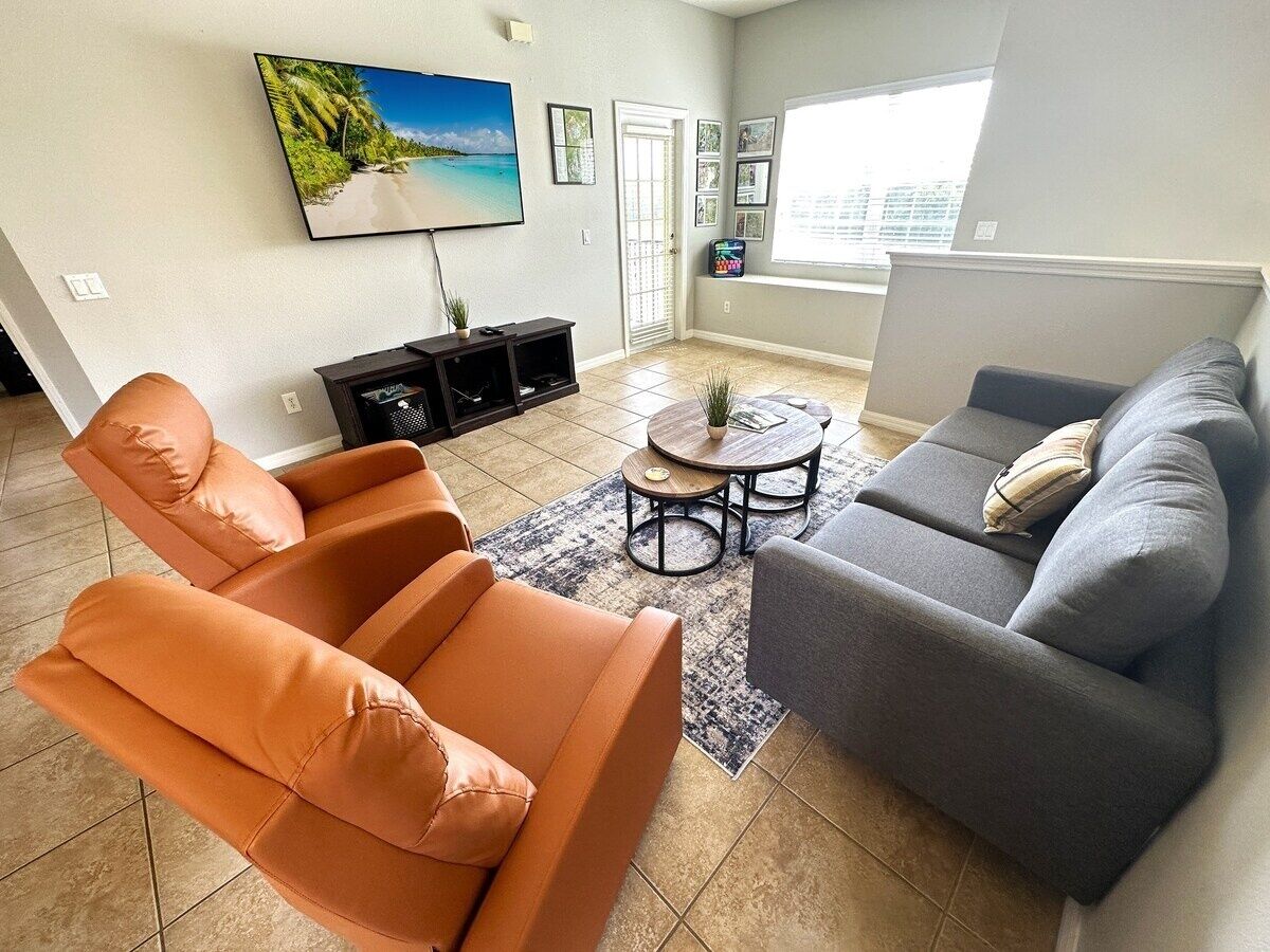 Un salon avec un canapé, des fauteuils, une table basse et un téléviseur.