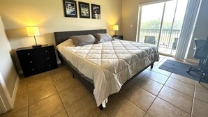 Ein Schlafzimmer mit Bett, Nachttischen, einem Balkon mit Blick und Bildern an der Wand.
