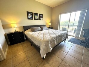 Ein Schlafzimmer mit Bett, Nachttischen, einem Balkon mit Blick und Bildern an der Wand.