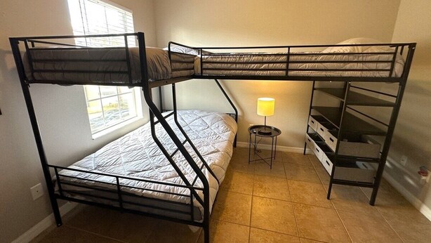 A bunk bed room with a window, a lamp, and a storage unit.