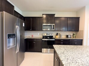 A modern kitchen with dark cabinets, stainless steel appliances, and granite countertops. - Villa Near Disney Themed Luxury 5bd With Pool 5 Bedroom Home (Kissimmee)