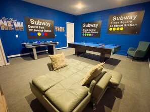 A room with a pool table, a sofa, and a sign indicating subway stations. - Villa Near Disney Themed Luxury 5bd With Pool 5 Bedroom Home (Kissimmee)