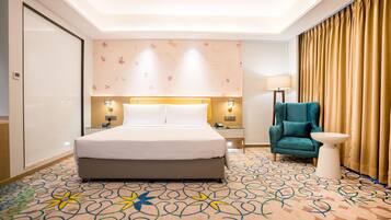 Een hotelkamer met een bed, een stoel, een klein tafeltje, een lamp en een kamerbreed tapijt met dessin.