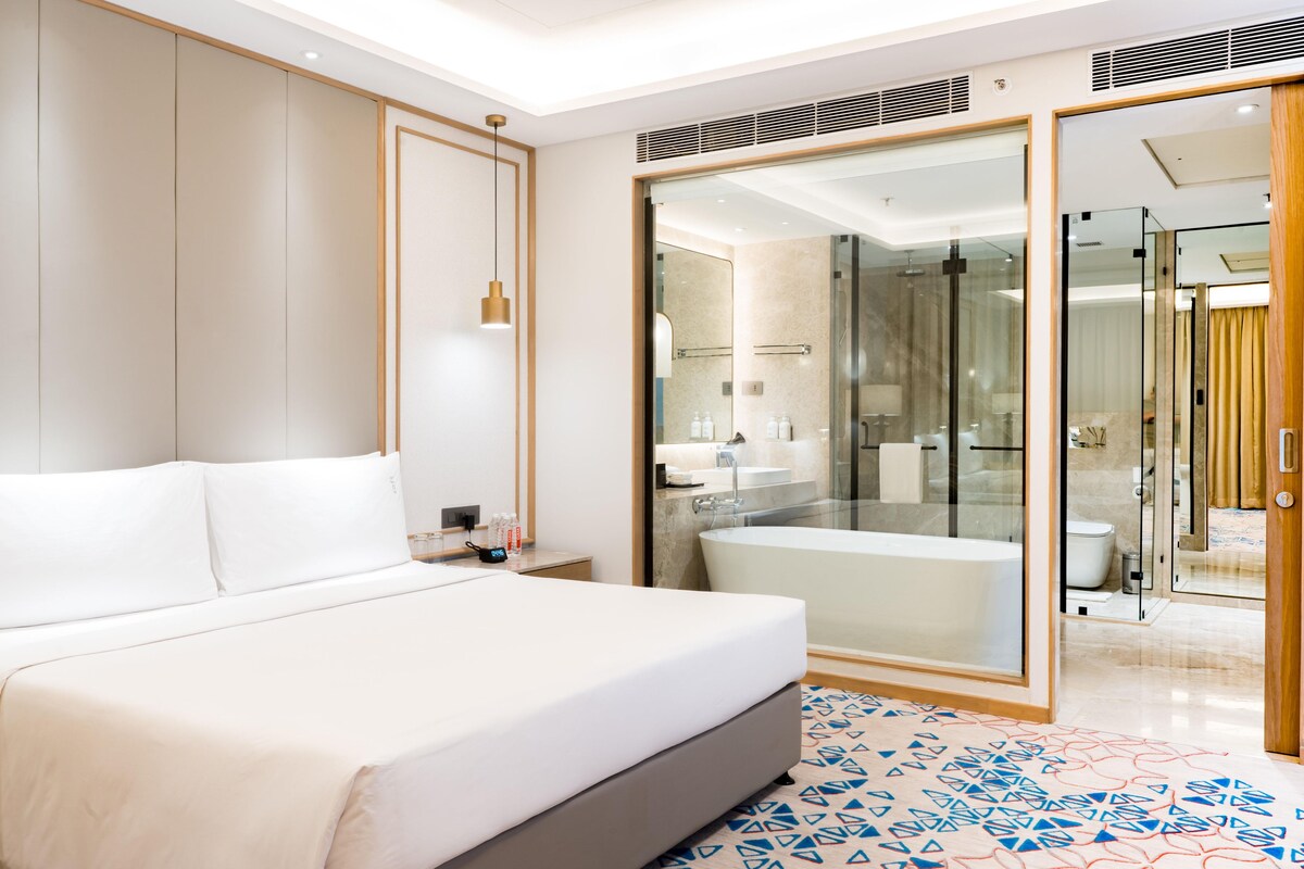 Een moderne hotelkamer met een groot bed, een douchecabine met glazen wanden en een apart badkamer.