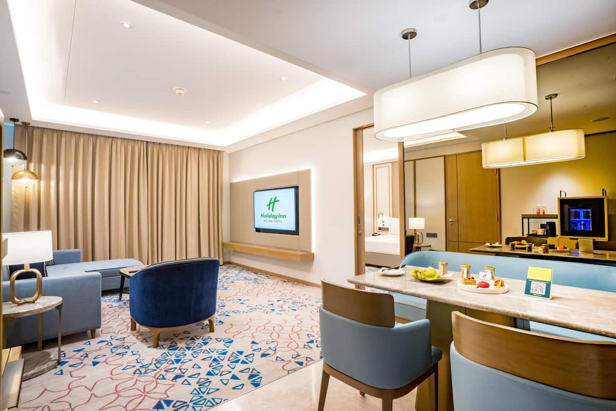 A hotel lobby with a seating area, a reception desk, and a television screen displaying the hotel name.