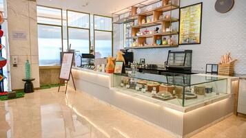 A modern cafe with a marble floor, a glass display case, and a menu board.