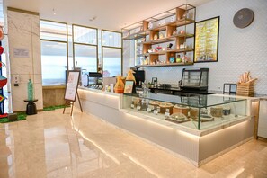 A modern cafe with a marble floor, a glass display case, and a menu board. - Holiday Inn Lucknow Airport (Lucknow)