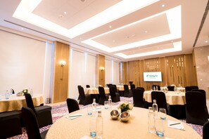 A conference room with round tables, black chairs, and a ceiling with recessed lighting. - Holiday Inn Lucknow Airport (Lucknow)