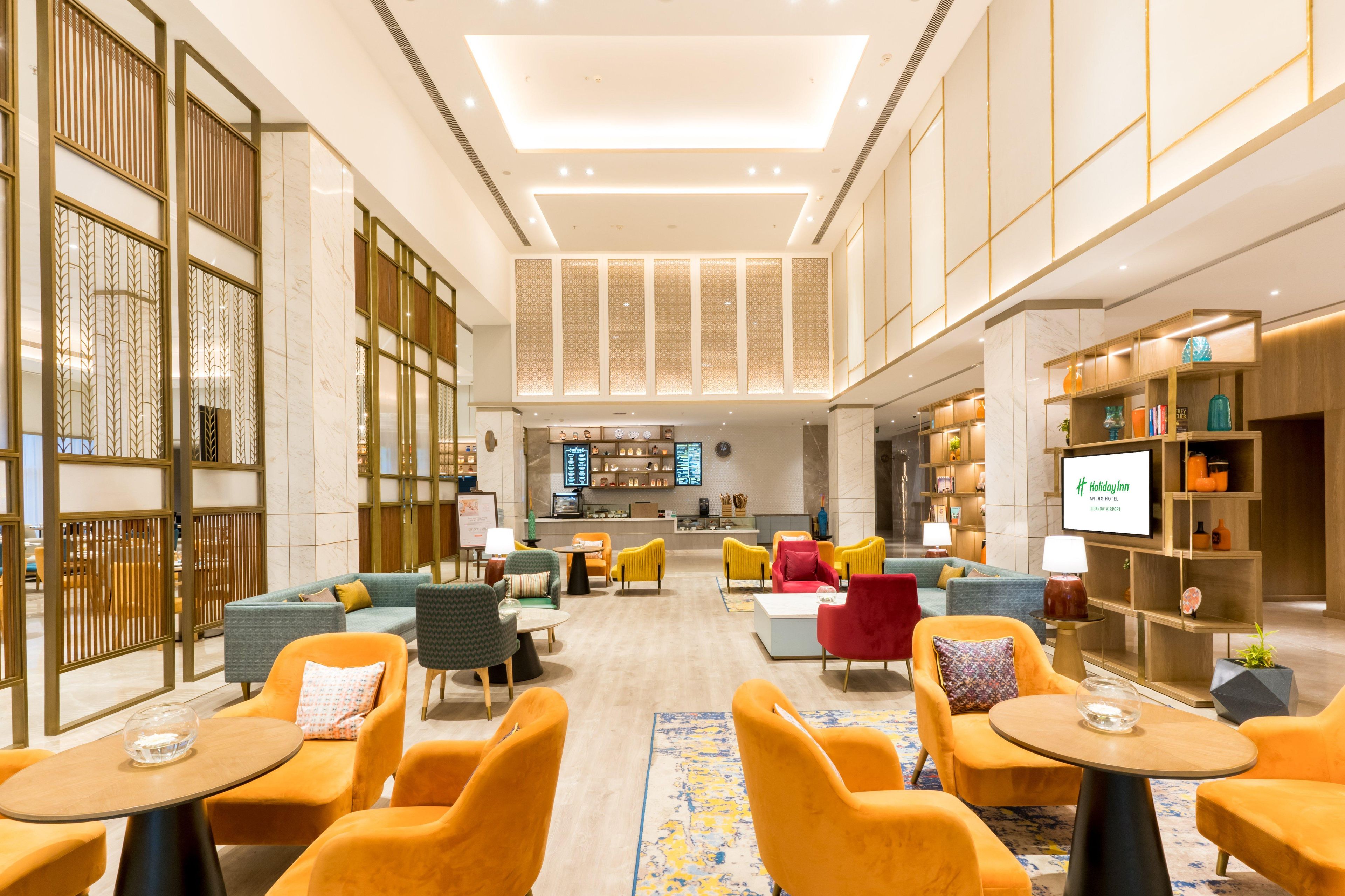 Eine geräumige Lobby mit Sitzbereichen, einem Empfangsbereich und einem Fernsehbildschirm, der 'Holiday Inn' anzeigt.