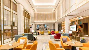 Eine geräumige Lobby mit Sitzbereichen, einem Empfangsbereich und einem Fernsehbildschirm, der 'Holiday Inn' anzeigt.