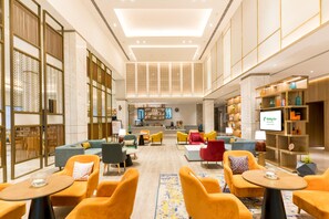 A spacious lobby with seating areas, a reception desk, and a television screen displaying 'Holiday Inn.' - Holiday Inn Lucknow Airport (Lucknow)