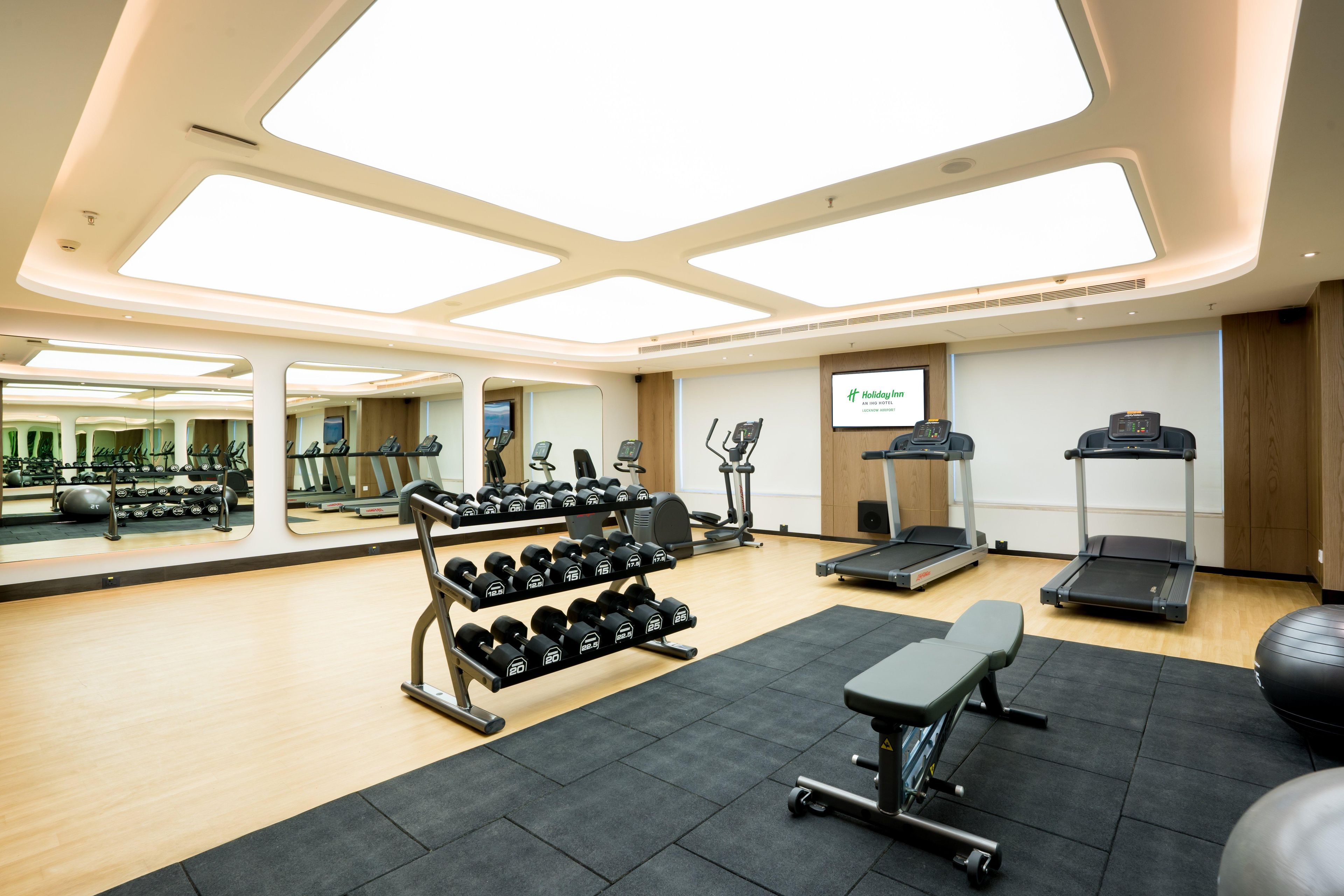 A gym with exercise equipment, mirrors, and a large window.