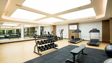 A gym with exercise equipment, mirrors, and a large window.