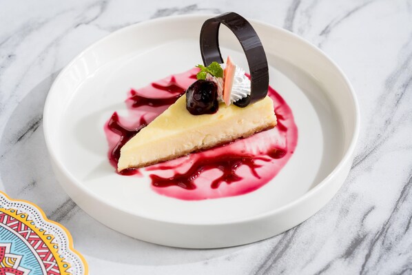 A dessert on a white plate with a decorative ring and a berry garnish. - Holiday Inn Lucknow Airport (Lucknow)